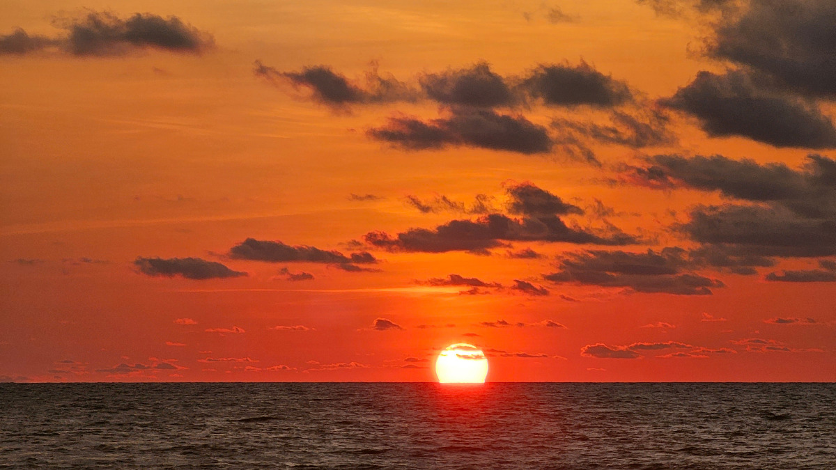 Home 3 A beautiful sunset in Negombo, Sri Lanka, bathed in shades of orange, with the sun disappearing behind the ocean