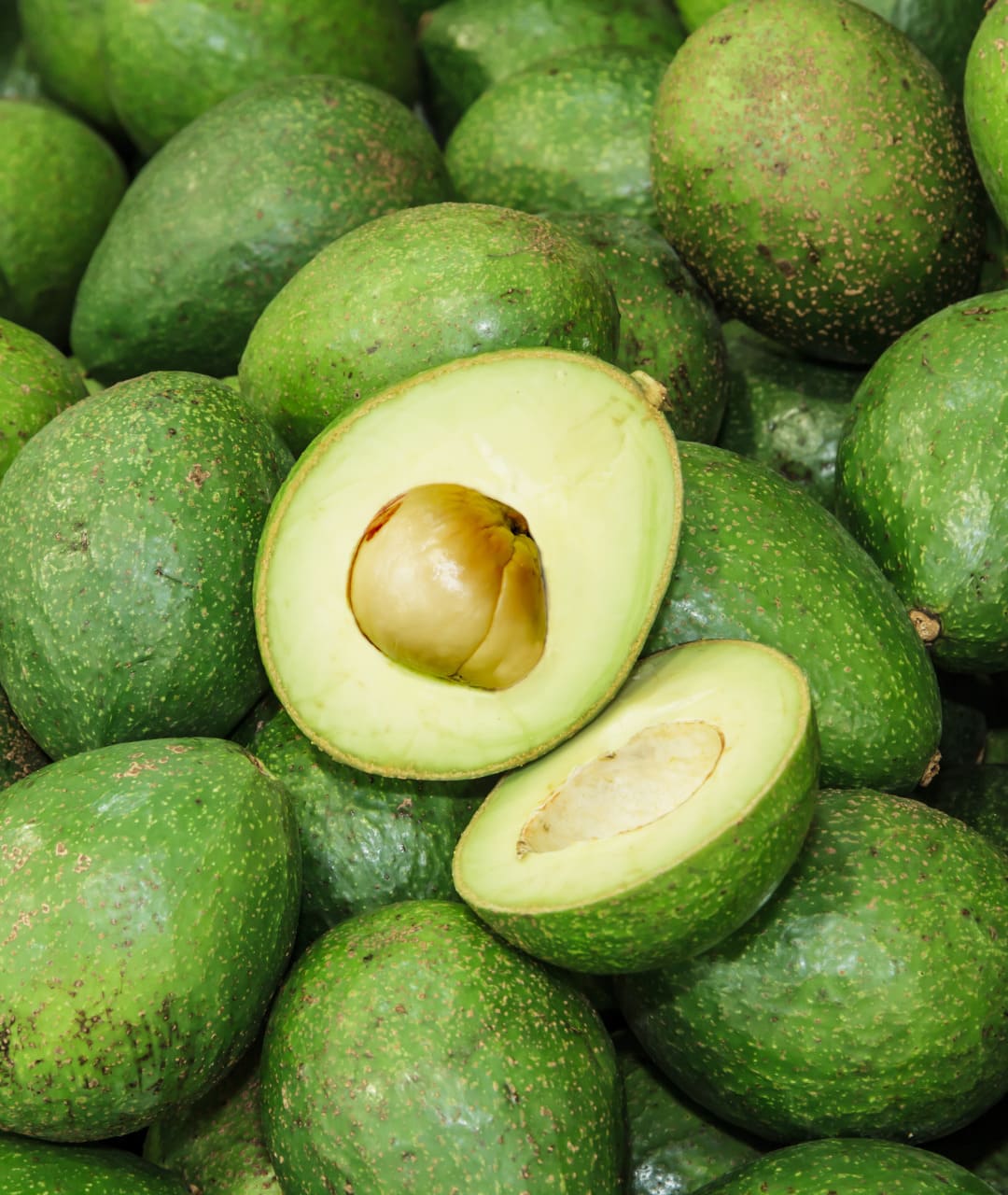 some avocados, one is open, so you can see the avocado inside.