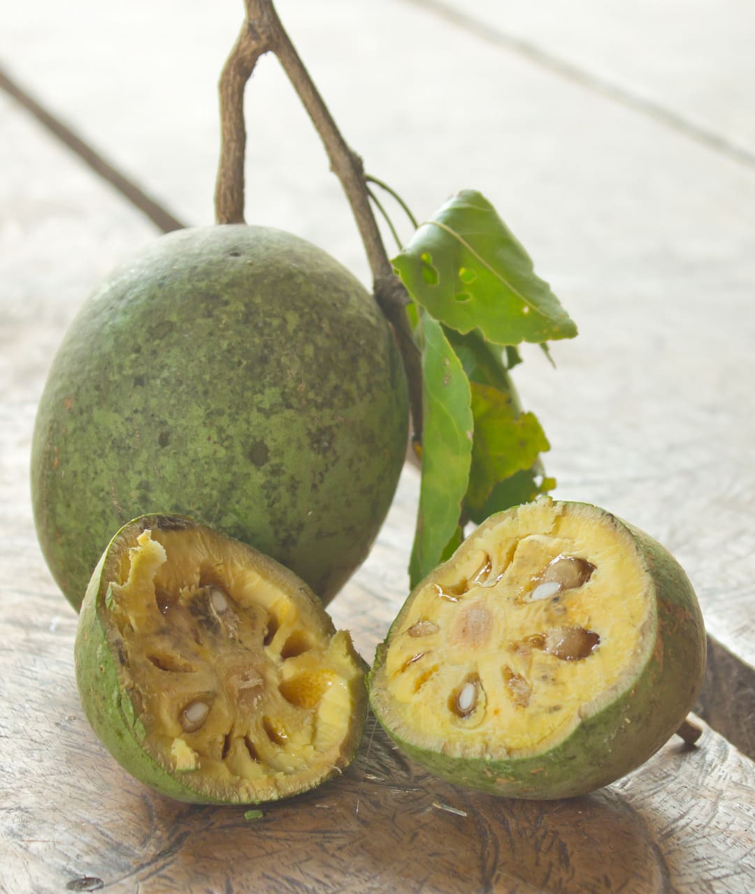the fruit beli from sri lanka on a table, one is open, so you can see the fruit from inside