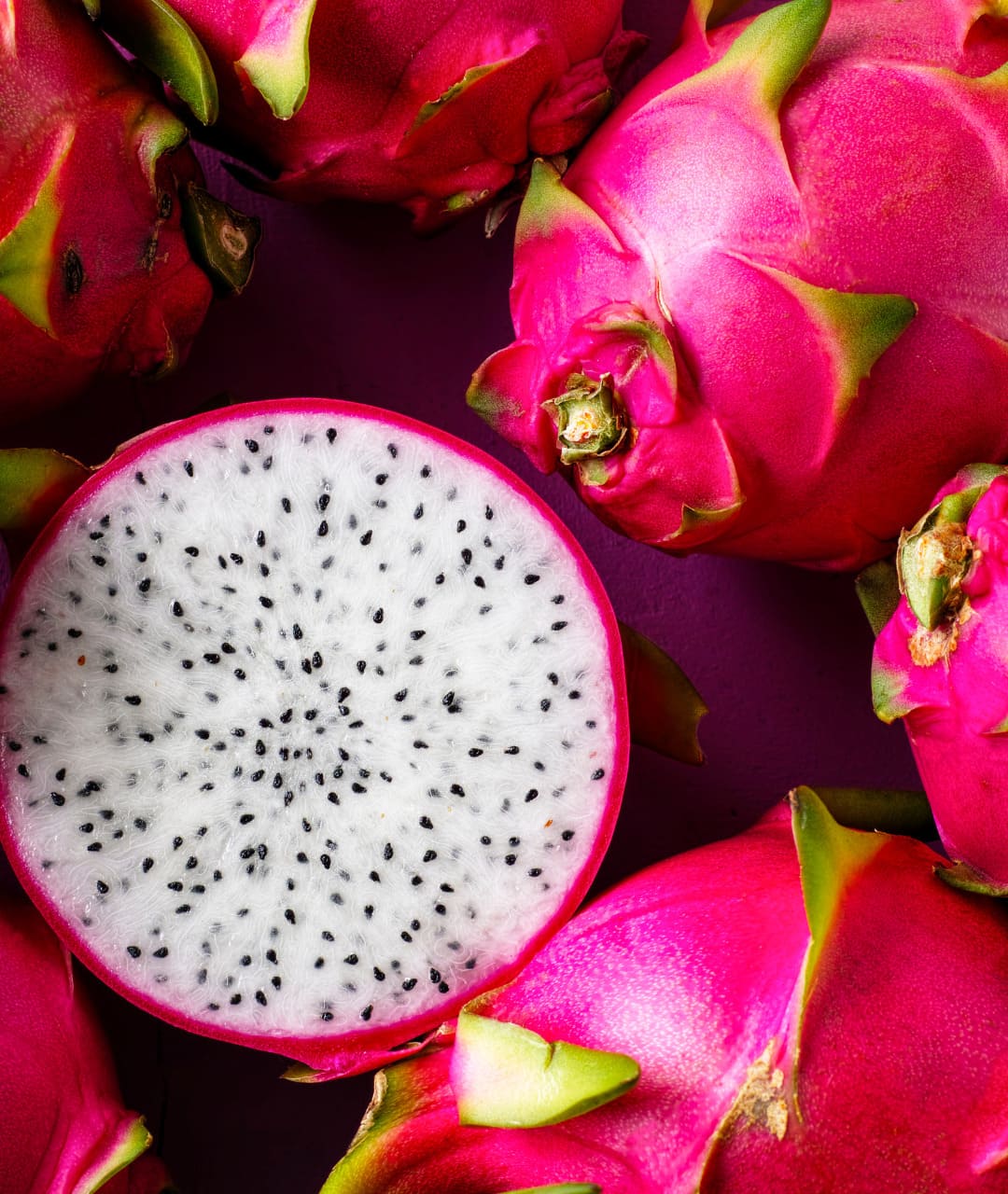 some dragon fruits, one is open, so you can see the fruit inside